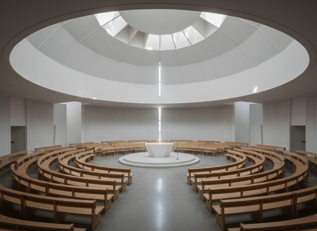 Modern circular church interior, geometric architecture, radial pews around a central altar, soft natural light, minimalist, no people, photographic style